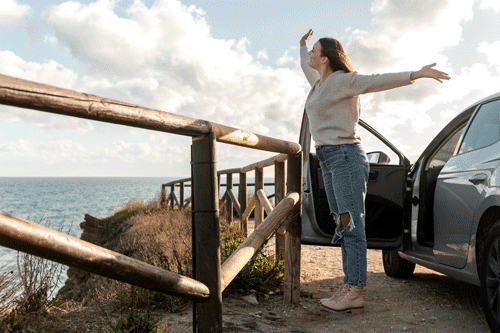 woman-enjoying-beach-breeze-while-car